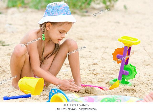 Funny five-year girl playing with sand molds on the beach