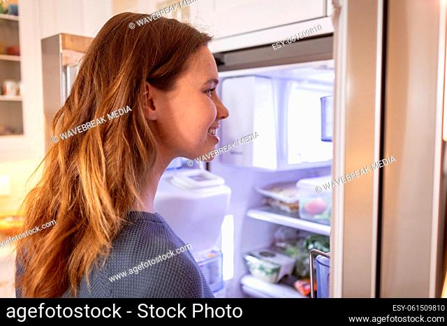 Woman opening the fridge at home