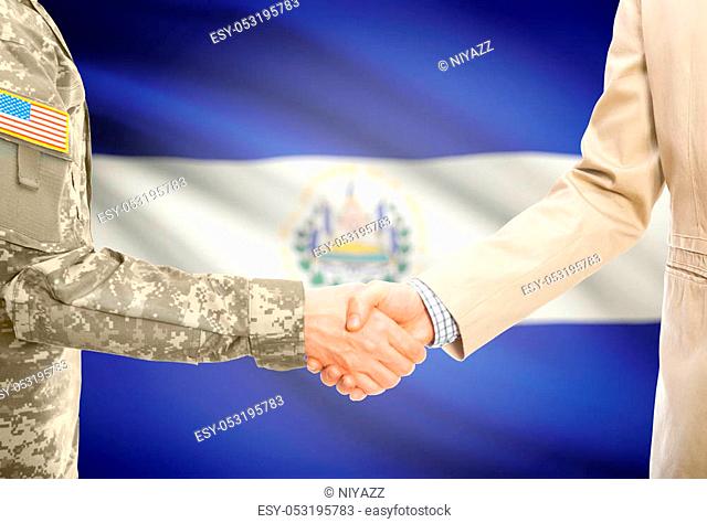 American soldier in uniform and civil man in suit shaking hands with national flag on background - El Salvador