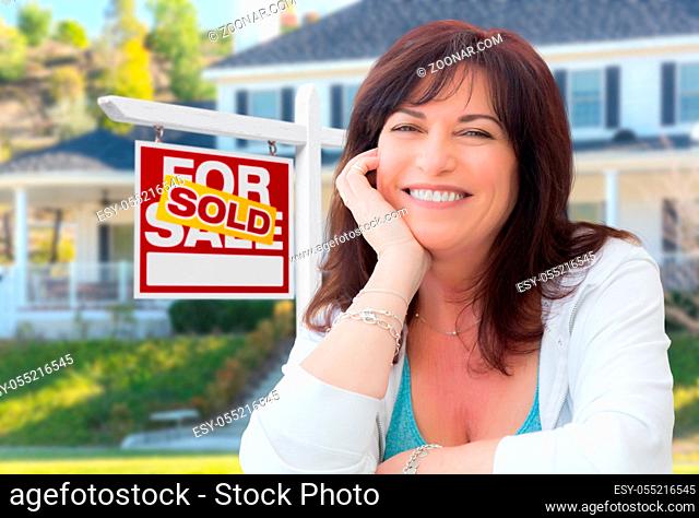 Middle Aged Woman In Front of House with Sold For Sale Real Estate Sign In Yard