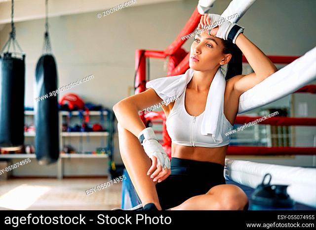 Young beautiful woman relax after fight or workout exercising in boxing ring. Sport concept