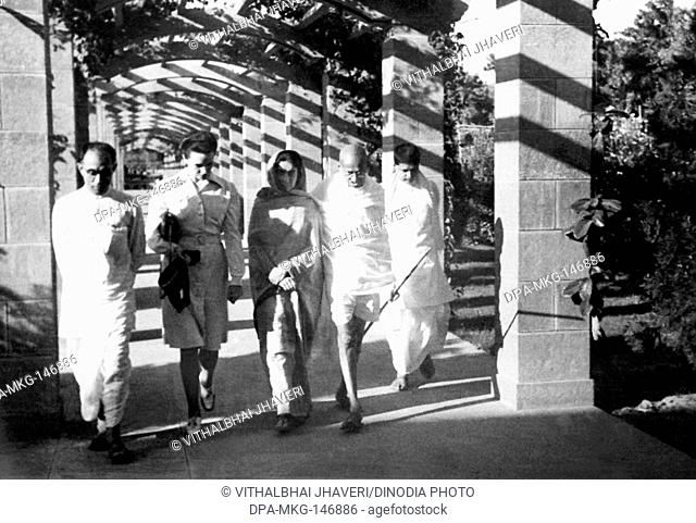 Mahatma Gandhi , walking with Pyarelal Nayar , his son Devdas and others , 1945 , India NO MR
