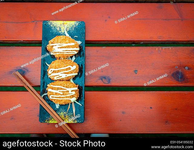 Top view of Potato Cutlet served in a long plate with chopsticks placed on a wooden surface