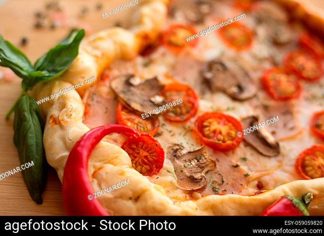 Pizza heart shaped with ham tomatoes and mushrooms on wooden background . Concept of romantic love for Valentines Day . Love food