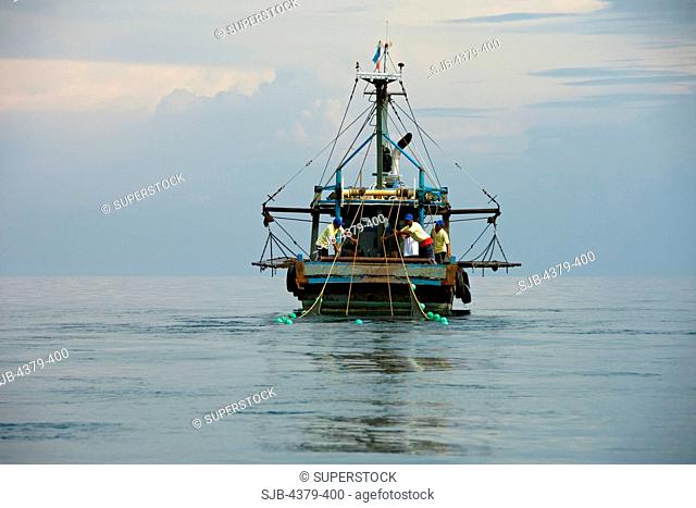 A small fishing trawler bringing in nets, South China Sea, East Malaysia