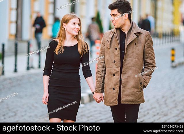 Urban modern young love couple walking romantic talking talking, holding hands on a date. Young multicultural Turkish brunette and Caucasian couple on old...