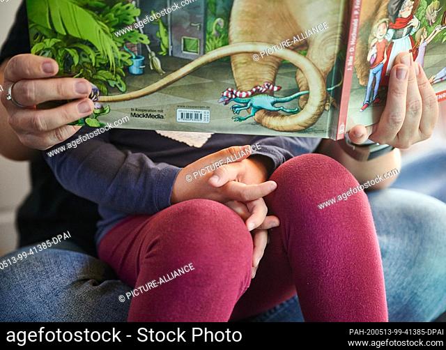 13 May 2020, North Rhine-Westphalia, Dortmund: Jacqueline Kreisel, educator at the Hainallee daycare center, looks at a picture book with a child