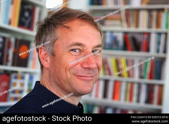 14 April 2022, Bavaria, Munich: Jo Lendle, writer and publisher of Carl Hanser Verlag, stands in front of books in his office