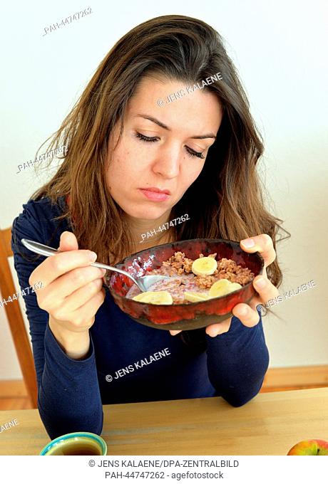 A young woman looks moody at a bowl of cereals in her hands in Berlin, Germany, 02 December 2013. Photo: Jens Kalaene - MODEL RELEASED | usage worldwide