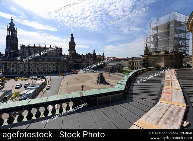 11 May 2021, Saxony, Dresden: The Quadriga (r) on top of the Semperoper is covered with scaffolding, in the background the old town on the Elbe with the...