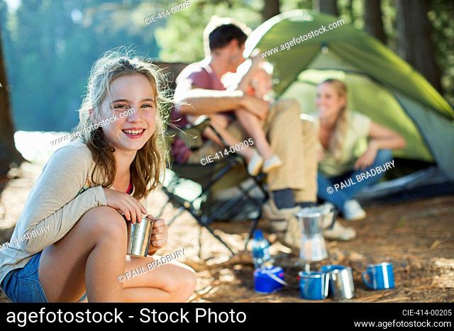 Smiling girl at campsite with family in woods