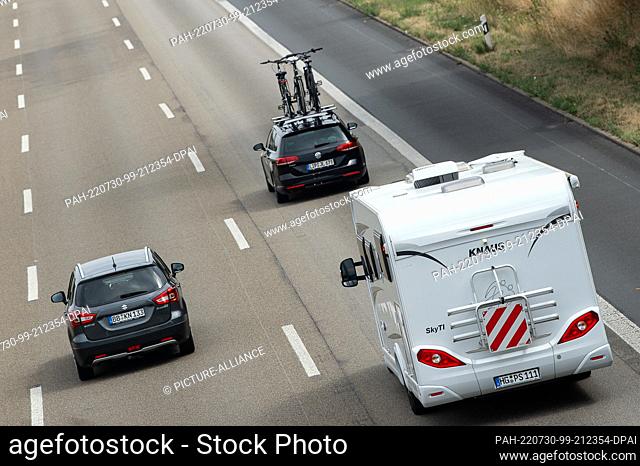 30 July 2022, Hessen, Kassel: A car with bicycles and a motorhome drive over the highway A7. On 29.07.2022 the summer vacations have also started in the last...