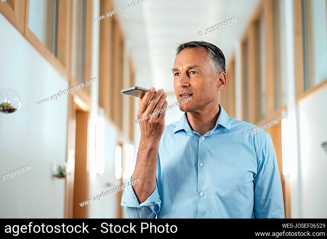Mature businessman using voicemail on smart phone in office