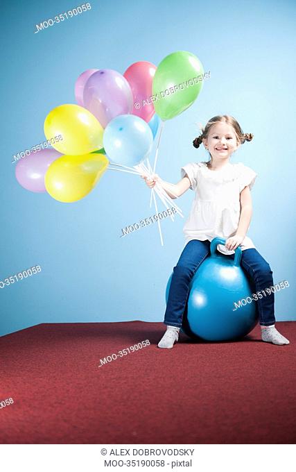 Young girl holding balloons on a hoppity horse