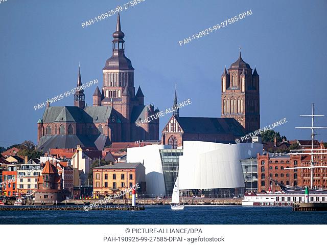 05 September 2019, Mecklenburg-Western Pomerania: Panoramic view over the Strelasund to the silhouette of the historic old town of Stralsund with the...