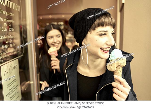 two women with ice cream cones coming out of ice café, in city Cottbus, Brandenburg, Germany