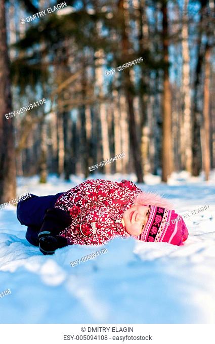 Baby lays on snow in wood