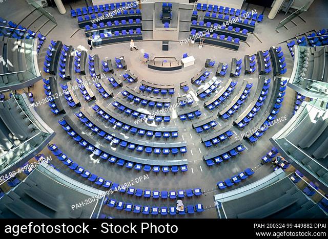 24 March 2020, Berlin: Members of the Bundestag staff put slips of paper with the inscription ""Bitte frei lassen"" on the chairs of the delegates in the...