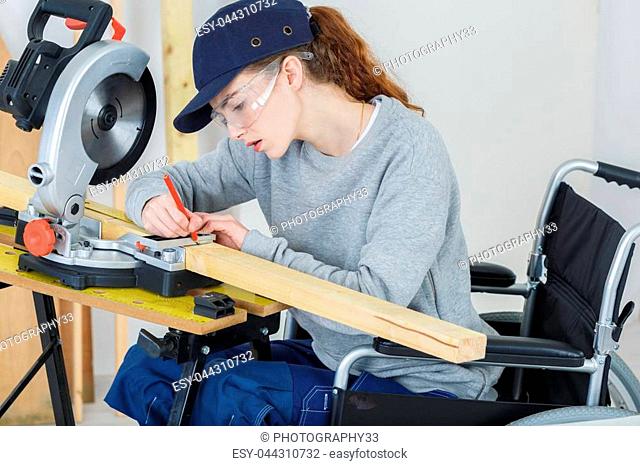 female carpenter on wheelchair using a circular saw