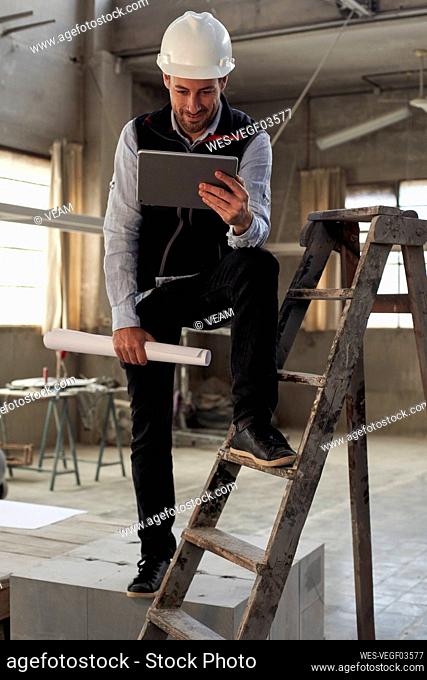 Male engineer using digital tablet while standing in building at site