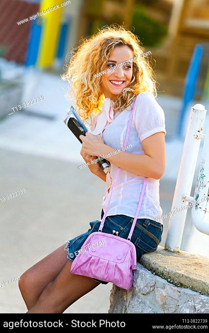 Teenage girl blonde curly hair looking back pleasantly surprised