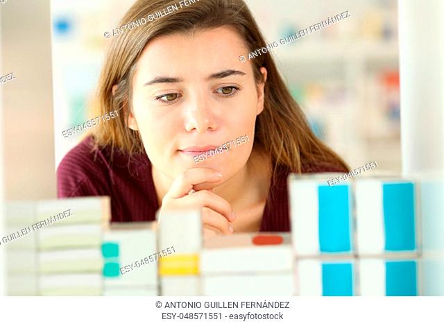 Front view of a doubtful customer choosing medicines in a pharmacy