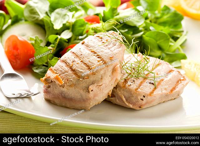 photo of grilled tuna steak with sald on green wooden table