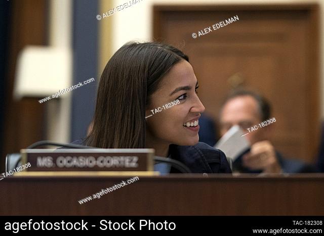 Representative Alexandria Ocasio-Cortez, D-N.Y., smiles as Federal Reserve Board Chairman Jerome Powell testifies before the House Financial Services Committee...