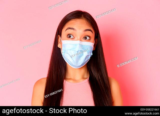 Covid-19 pandemic, coronavirus and social distancing concept. Close-up of curious and surprised attractive asian girl in medical mask