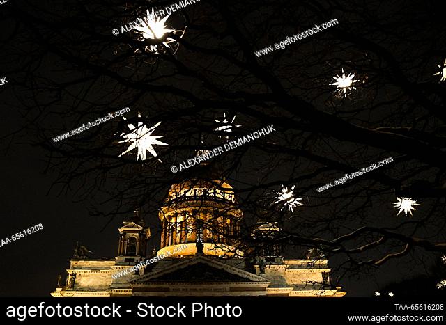RUSSIA, ST PETERSBURG - DECEMBER 10, 2023: Star-shaped lights hang from tree branches, with St Isaac's Cathedral in the background
