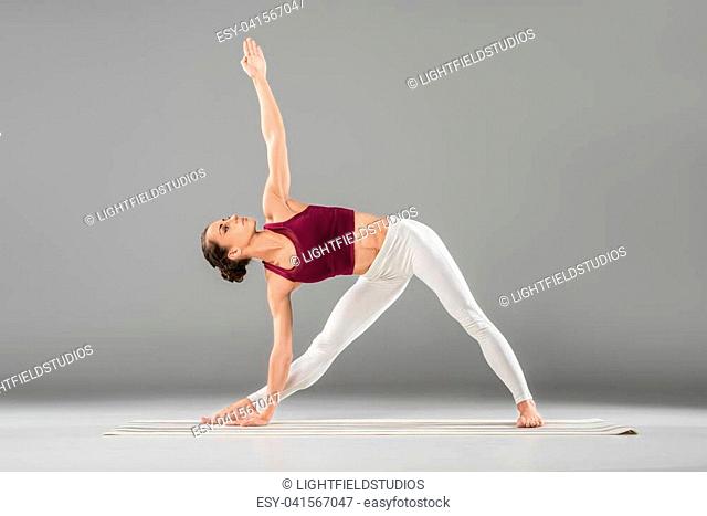 woman practicing yoga, standing in Extended Side Angle exercise, Utthita parsvakonasana pose