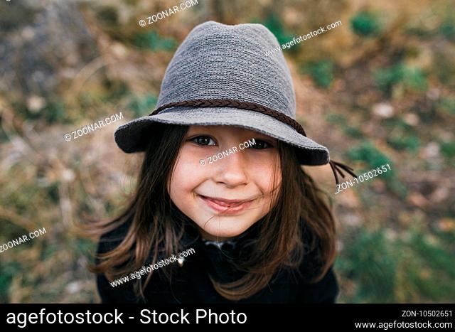 little girl in a black coat and hat posing in autumn park