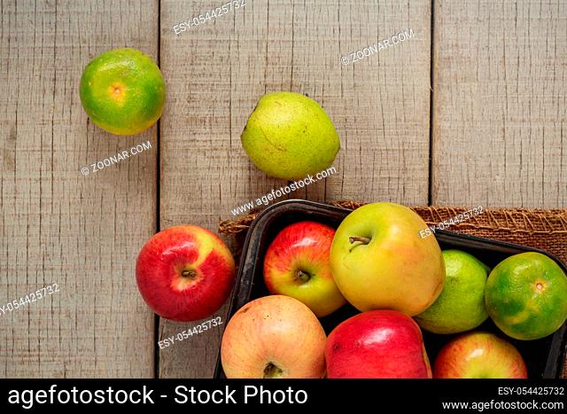 Apple in tray and oranges on wooden floor