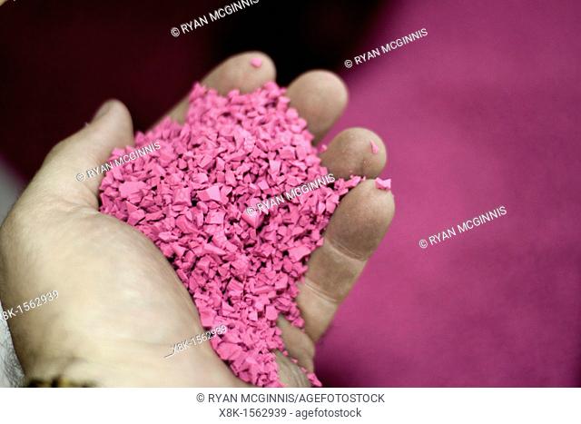A man holds Pink plastic 'nurdles' shredded plastic raw materials ready to be loaded into the hopper of a plastic molding injection machine