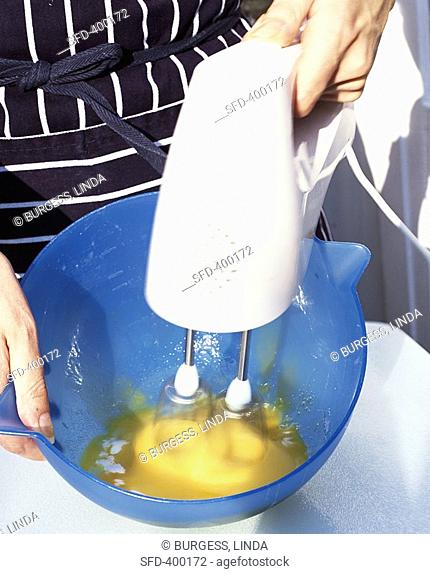 Mixing egg yolk and sugar with an electric hand mixer