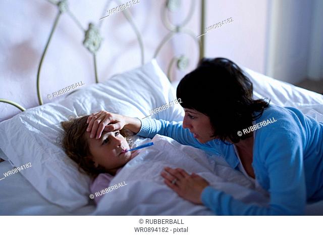 High angle view of a mother checking her daughters temperature