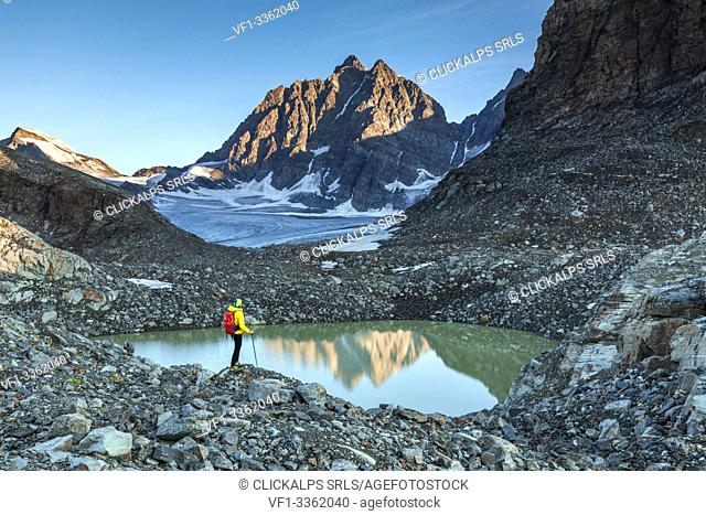 Hiker standing on the shore of epiglacial lake next to Fellaria Glacier, Malenco Valley, Sondrio Province, Valtellina, Lombardy, Italy
