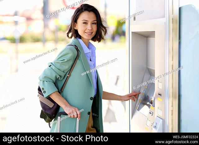 Smiling female professional buying train ticket at railroad station