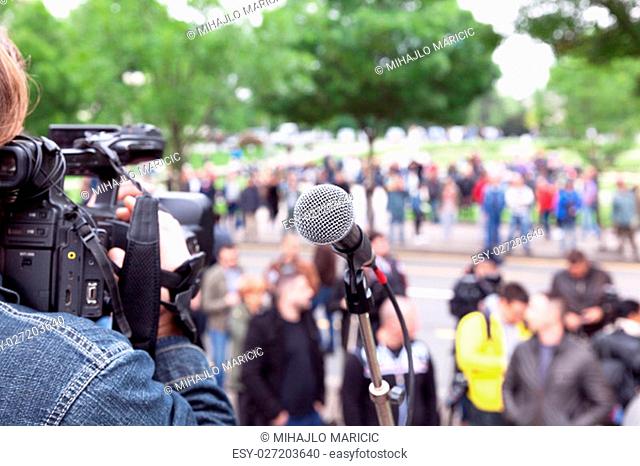Microphone in focus, camera operator shooting blurred crowd