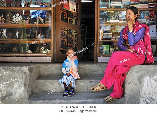 Mother and daughter sitting in front of the book shop in New Manali. Manali, Himachal Pradesh, India