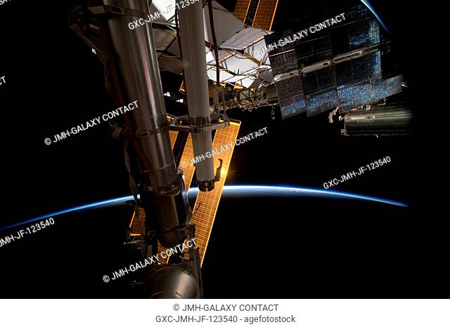 Backdropped by the thin line of Earth's atmosphere and the blackness of space, a portion of the International Space Station is featured in this image...