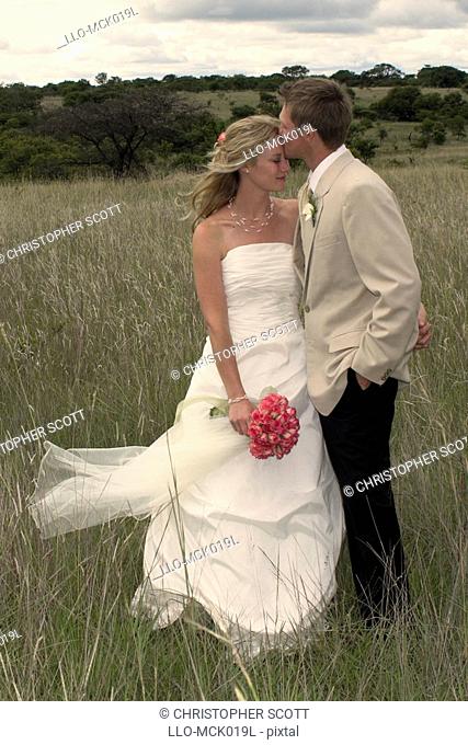 Bride and Bride Groom Embracing in a Field of long Grass  Antelope Park, Gweru, Midlands Province, Zimbabwe, Southern Africa