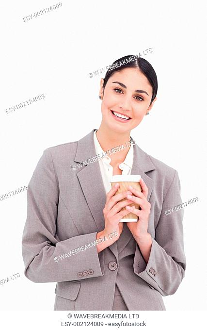 Smiling businesswoman holding paper cup against a white background