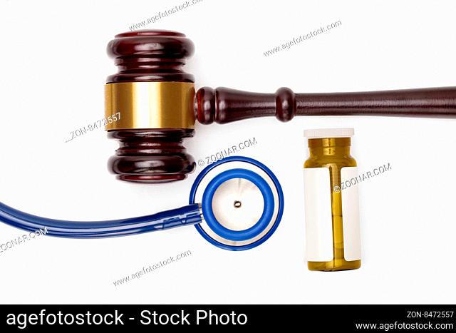 Wooden judge gavel, pills bottle and stethoscope on white backround