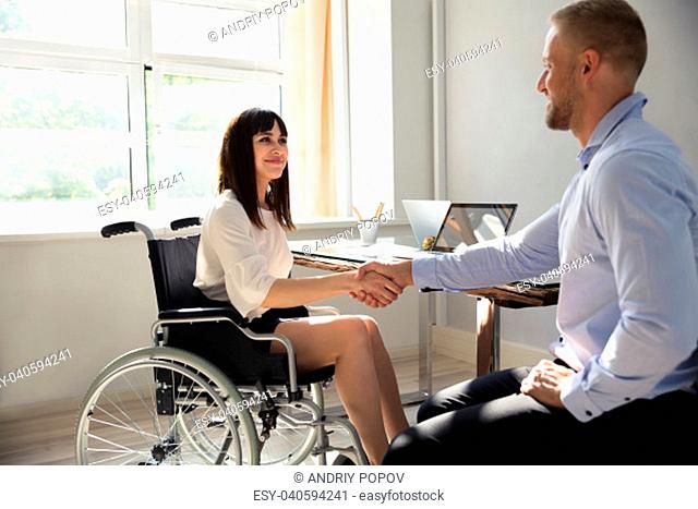Happy Disabled Businesswoman Sitting On Wheelchair Shaking Hand With Her Partner