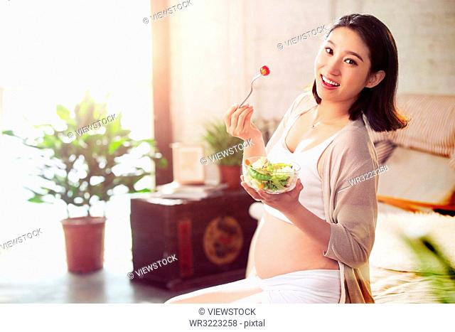 Pregnant women are eating vegetable salad