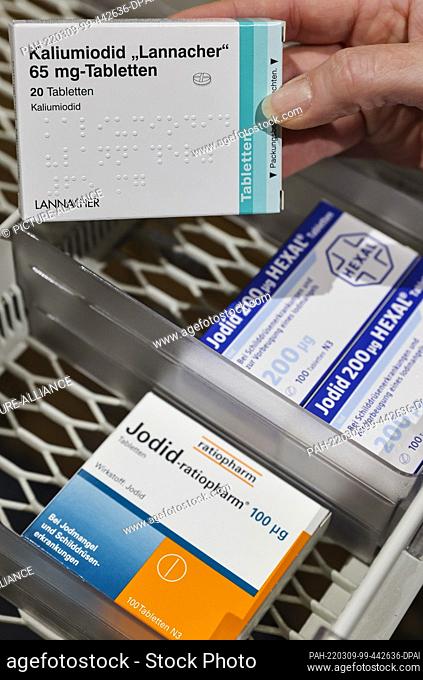 08 March 2022, Saxony, Leipzig: A pharmacist takes a pack of high-dose iodine tablets from a supply cabinet, next to which are weaker doses for thyroid...