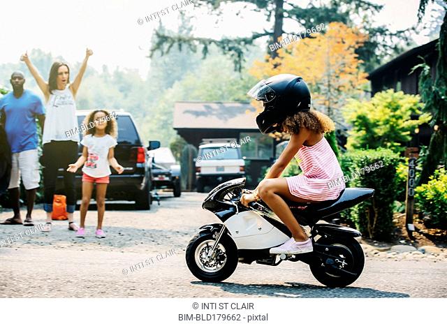 Girl riding miniature motorcycle on street
