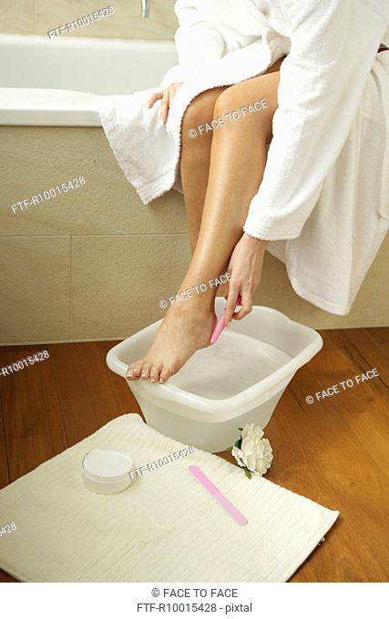 A woman cleaning her foot in the bathroom