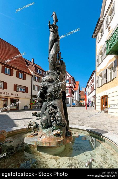 Germany, Baden-Wuerttemberg, Riedlingen, Narrenbrunnen at Weibermarkt. The fool's fountain column from 1997 by the artist Gerold Jäggle shows scenes from the...